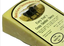A slice of Farmhouse Fiery Fred Cheddar cheese wrapped in paper with a label on top, placed against a white background.