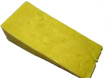 A slice of Farmhouse Mild Cheddar cheese placed against a white background.