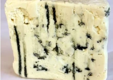 A slice of Point Reyes Original Blue cheese, showcasing its creamy interior with blue veining, is set against a grey background