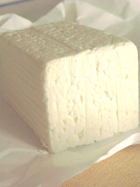A block of Quartirolo Lombardo, showcasing its soft, crumbly texture, placed on paper.