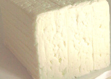 A block of Quartirolo Lombardo, showcasing its soft, crumbly texture, placed on paper.