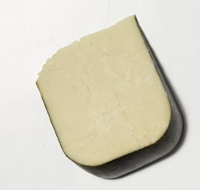 A slice of Seascape cheese, showcasing its creamy texture, rests against a grey background