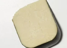 A slice of Seascape cheese, showcasing its creamy texture, rests against a grey background