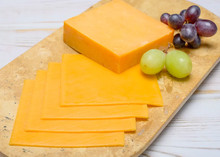 Blocks and slices of yellow American Cheese 168开奖官方开奖结果查询 幸运8官网开奖官方结果 直播历史记录查询 arranged on a wooden cutting board
