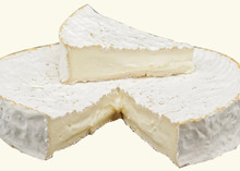 A wheel of Brie Cheese 168开奖官方开奖结果查询, partially sliced, sits on a white surface with triangular piece of brie sits on the top of the wheel