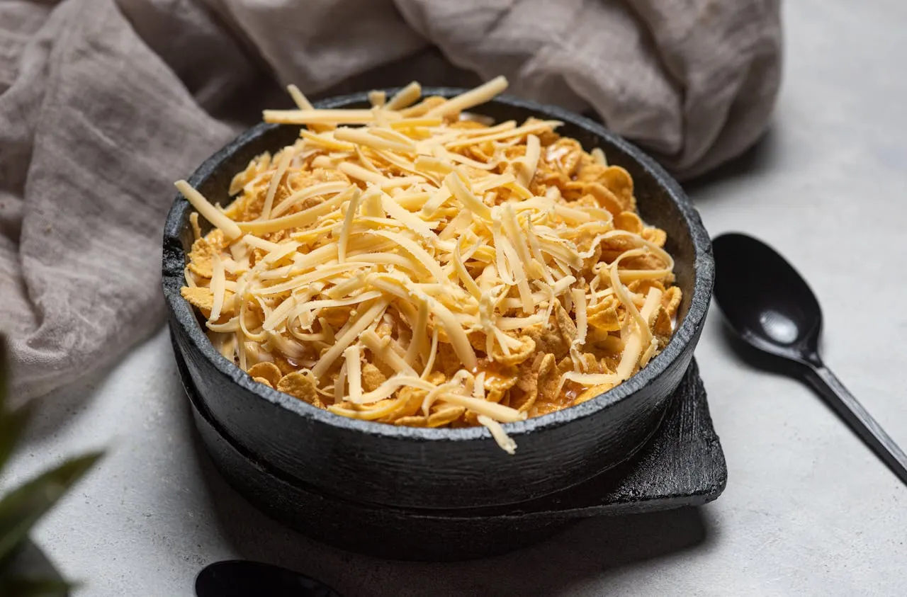 A bowl of cornflakes with grated Monterey Jack cheese